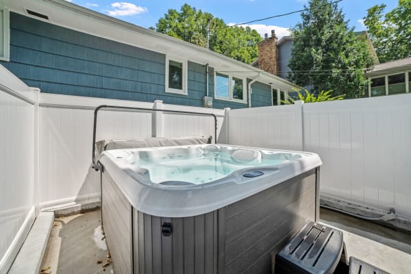 Hot tub in a backyard setting with a fence and blue sky.