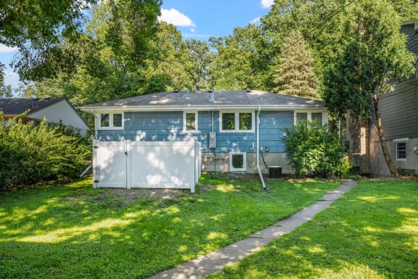 A single-story blue house with a well-maintained lawn and trees.