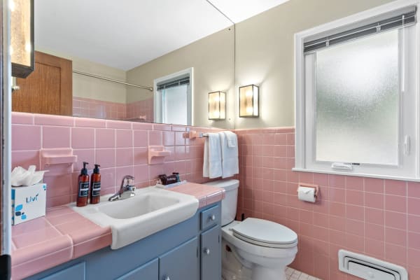 A bathroom featuring pink tile walls, a white sink, and modern fixtures.
