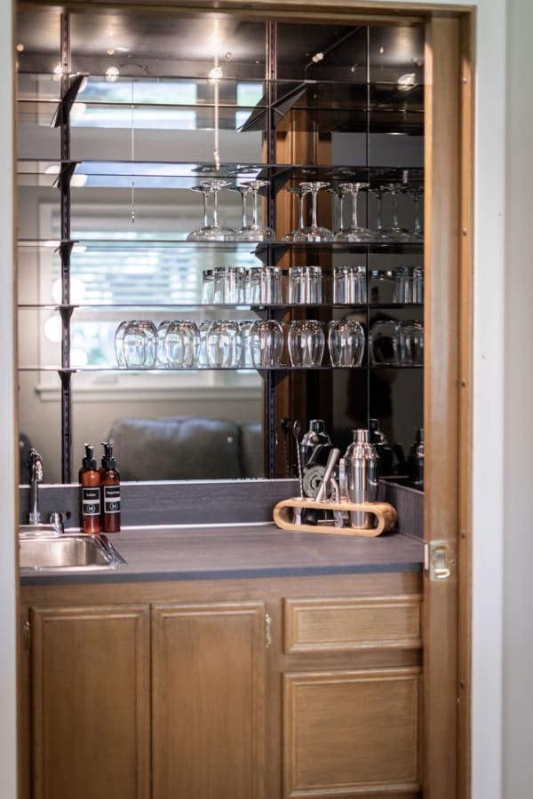 A modern home bar area showcasing glassware, a sink, and cocktail-making tools.