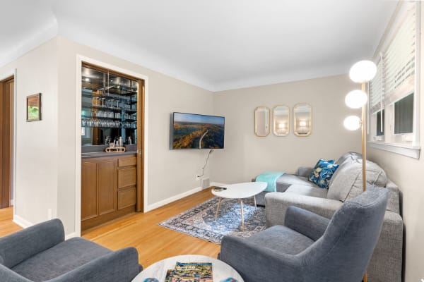 A cozy living room with a gray sectional sofa, a minimalist coffee table, and a bar area with glassware.
