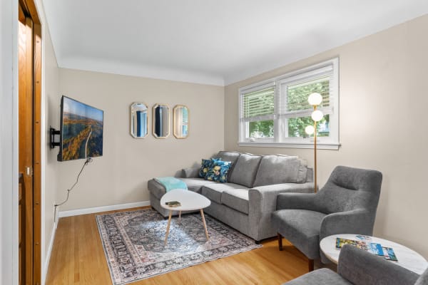 Living room featuring a gray sofa, decorative pillows, a coffee table, and a flat-screen TV on the wall.
