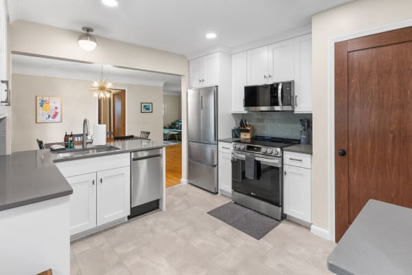 A contemporary kitchen featuring white cabinets, gray countertops, and stainless steel appliances.
