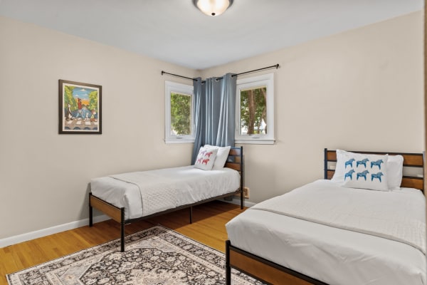 Cozy bedroom with twin beds, decorative pillows, and artwork on the walls.