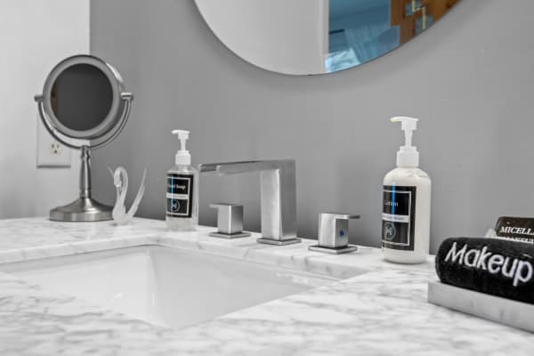 Contemporary bathroom countertop with sink, soap, lotion, and a mirror.