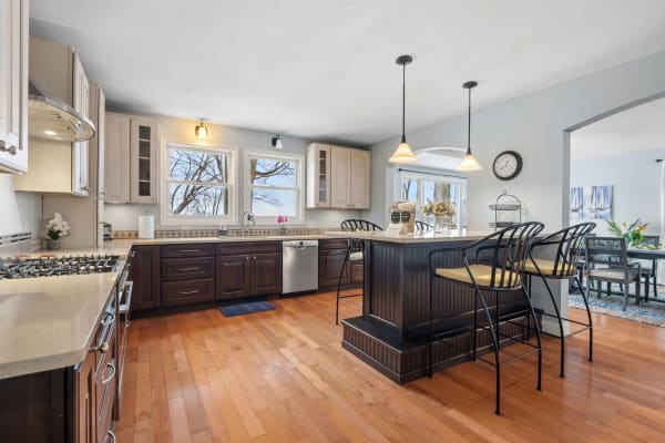 Modern kitchen with dark cabinetry, light countertops, and an island with bar stools.