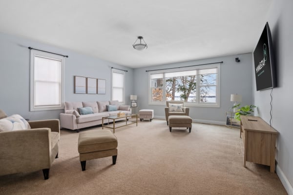 Spacious living room with light blue walls, sectional sofa, and natural light from large windows.