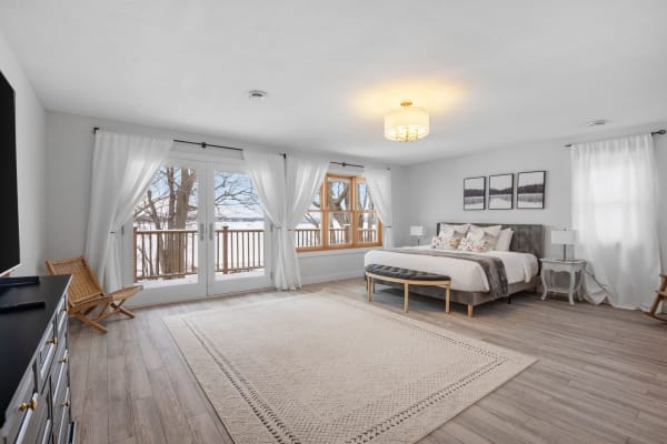 Cozy bedroom with gray bed, large windows, and a view of the winter landscape.