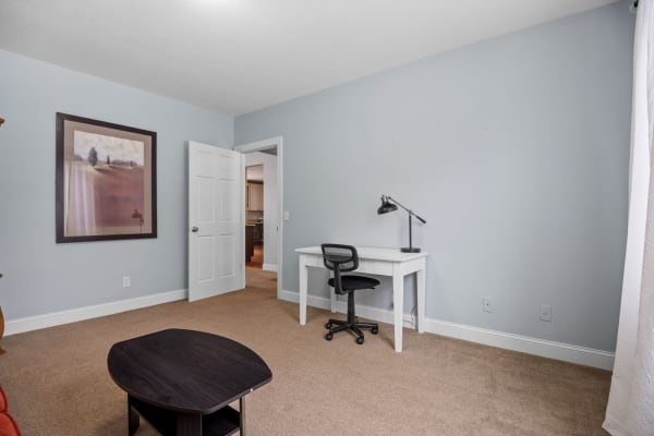A simple room with a desk and chair, featuring light blue walls and a small coffee table.