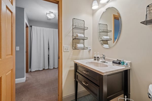 A stylish bathroom with a black vanity, light countertop, and neatly arranged towels on shelves.