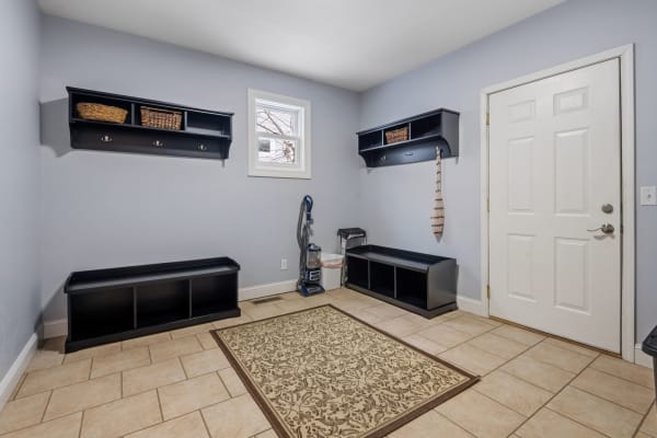 A mudroom featuring black shelving, a bench, and a decorative rug.