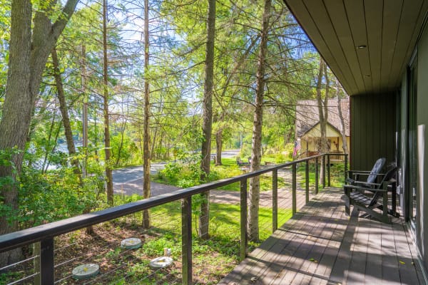 View from a balcony surrounded by tall trees and a path leading to a house.