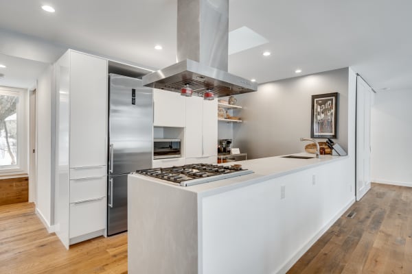 Modern kitchen with stainless steel appliances and wooden flooring.