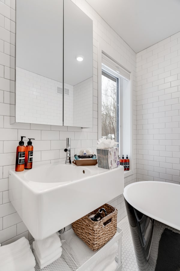 Modern bathroom with white subway tiles, a wall-mounted sink, and a black bathtub.