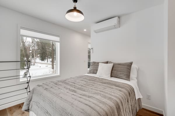 Cozy modern bedroom with a bed dressed in gray and winter scenery outside the window.