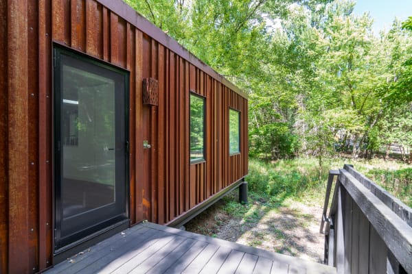 A contemporary structure with a rusty exterior and large windows set in a green landscape.