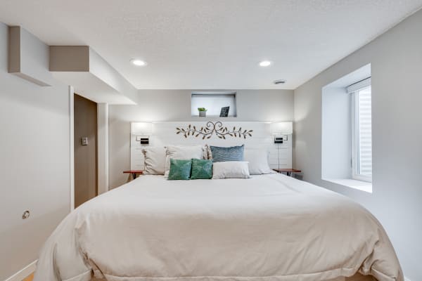 Modern bedroom with white bedding and decorative pillows.