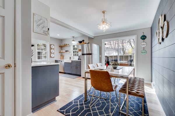 Bright dining space featuring a contemporary table, leather chairs, and a glimpse of the kitchen.