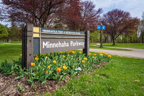 Sign for Minnehaha Parkway featuring tulips in bloom, with a pathway visible in the background.