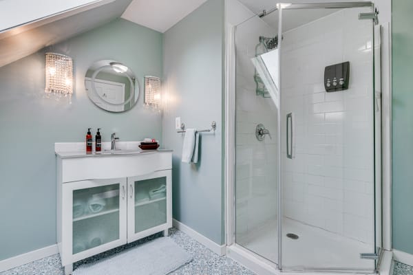 Modern bathroom with a glass shower, stylish vanity, and crystal sconces.