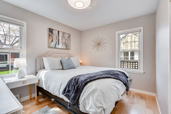 Cozy bedroom with a bed, nightstand, and wall decor in soft colors.
