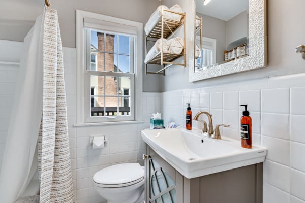 A contemporary bathroom featuring a white sink, bronze faucet, and neatly arranged towels.