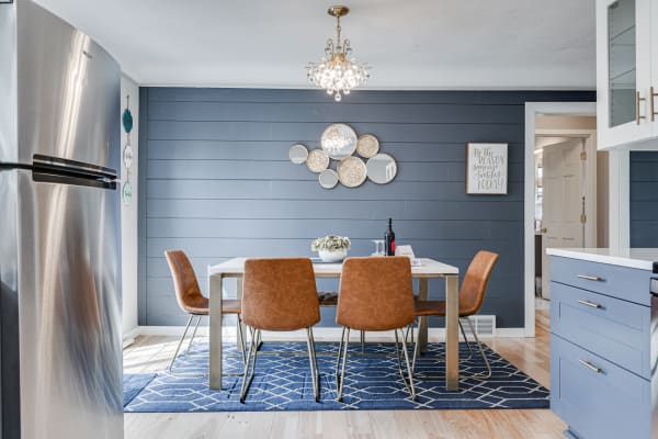 A contemporary dining space featuring a white table, brown leather chairs, and blue wall decor.