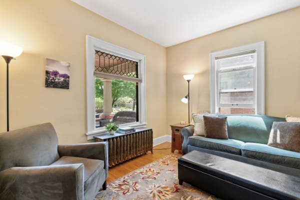 A comfortable living room corner with a gray armchair, teal couch, and decorative items.