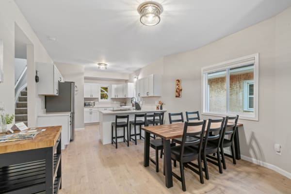 Modern kitchen and dining area featuring white cabinets, a wooden table, and ample natural light.