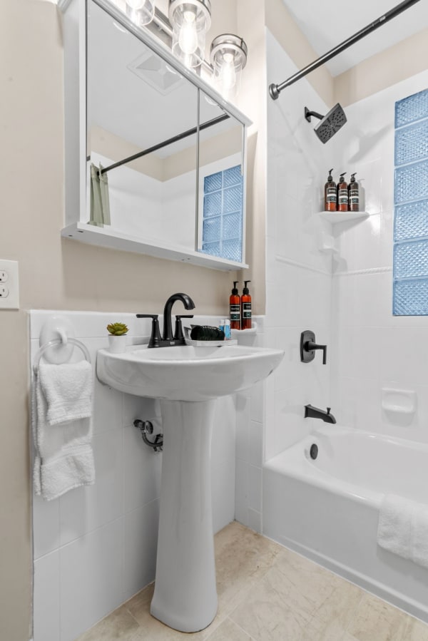 Simple and stylish bathroom with a white pedestal sink and glass block window.
