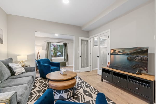 Modern living room featuring grey sofa, blue armchairs, and a large TV.