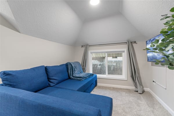 Cozy nook with blue sectional couch, window, and television.