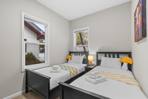 Cozy twin bedroom featuring two beds, a lamp, and colorful artwork.