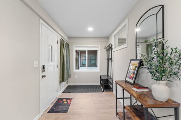 Modern entryway with a white front door, green curtains, and a wooden console table.