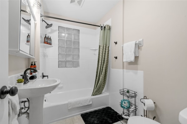 A clean and modern bathroom view featuring a bathtub, sink, and organized shelves.