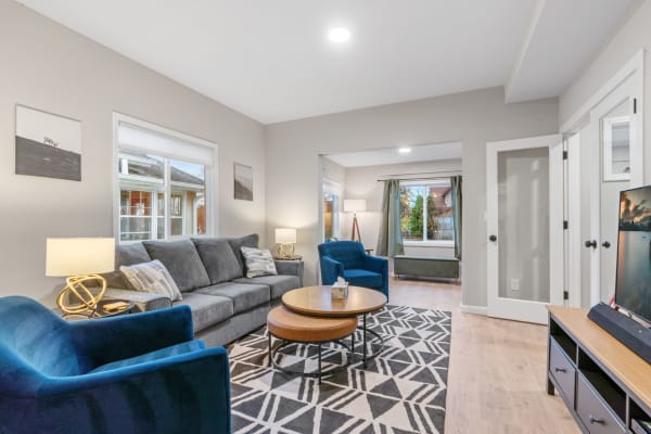 Cozy living room with gray sofa, blue chairs, and a geometric rug.