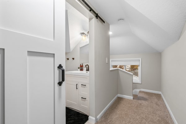 Cozy loft bathroom featuring a white vanity and soft beige walls with a sliding barn door.