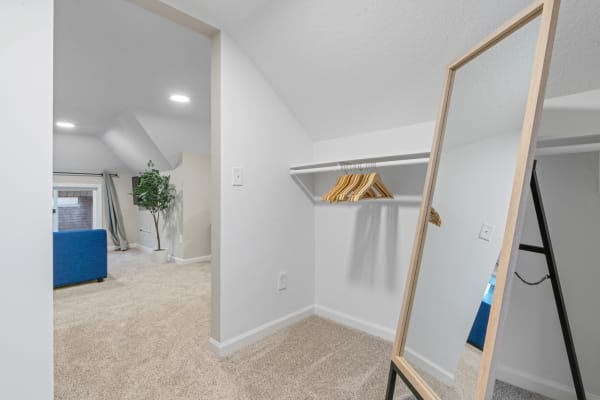 Attic room with a mirror, hangers, and a blue sofa.
