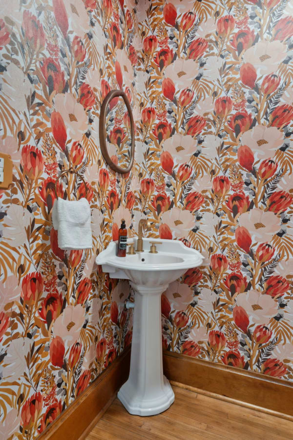 Bright bathroom with floral wallpaper and a white pedestal sink.