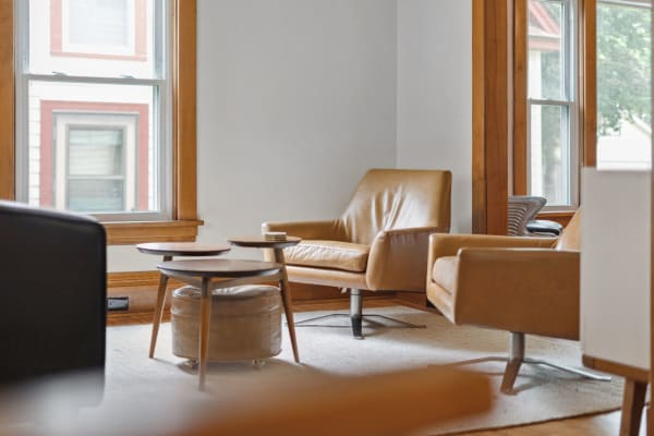 Cozy living room corner with tan leather chairs and a small wooden table.