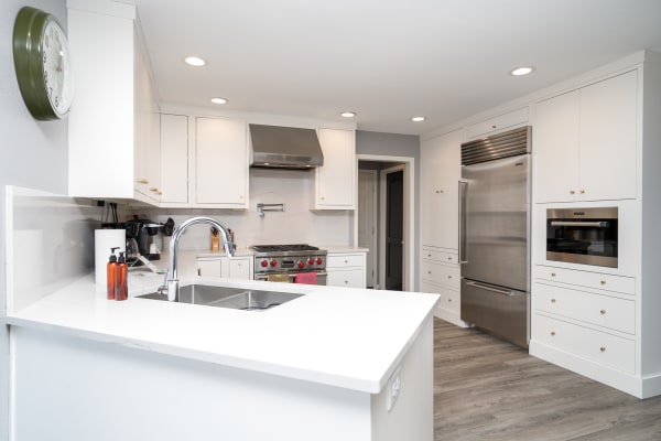 Bright and airy kitchen featuring white cabinets, stainless steel appliances, and a marble countertop.