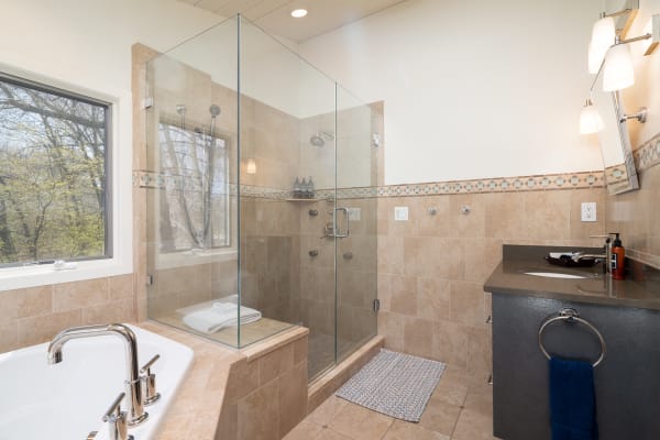 Modern bathroom with a glass shower, freestanding tub, and dark vanity.