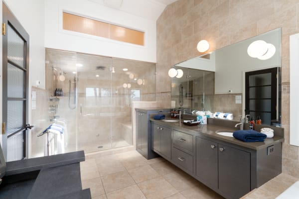 Stylish contemporary bathroom with a walk-in shower, dark cabinetry, and warm lighting.