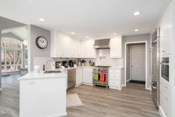 A spacious kitchen featuring white cabinetry, stainless steel appliances, and a view to the outdoors.
