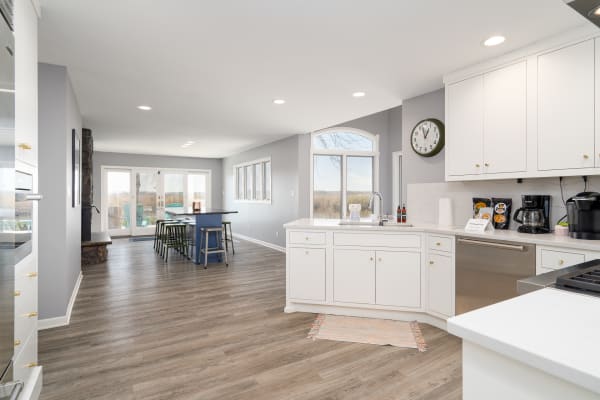 A bright and modern kitchen leading to a dining area with colorful accents and large windows.