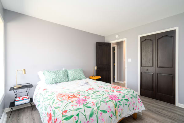 A modern bedroom featuring a floral bedspread, green pillows, and stylish furnishings.