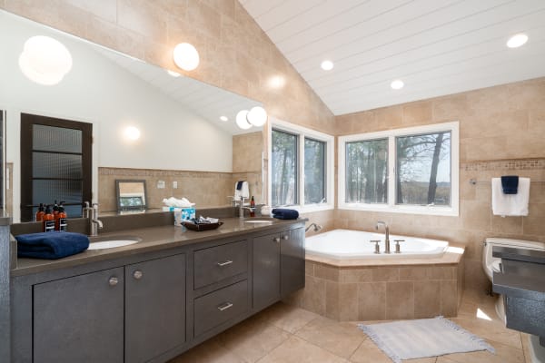 Modern bathroom featuring a double vanity, a bathtub, and natural stone tiles.