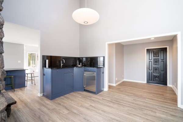 Contemporary kitchen with navy cabinets and black granite countertops, featuring a decorative black door.