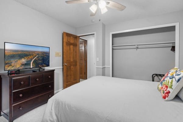 Cozy bedroom with a television, dresser, and floral pillow.
