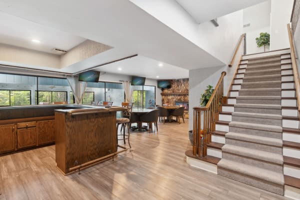 Spacious living area featuring a bar, seating, and a staircase.